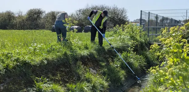 A water quality scientist collects a water sample from a stream